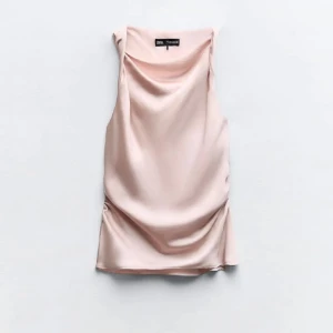 Ljusrosa ärmlös tröjafrån Zara - En elegant och stilren ljusrosa klänning från Zara. Klänningen är ärmlös och har en mjuk, draperad design som ger en smickrande passform.