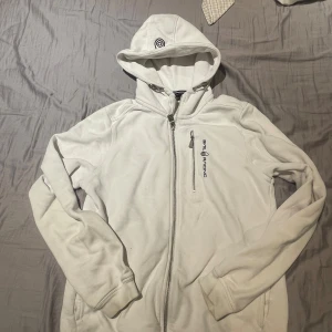Sailracing hoodie  - Säljer min vita Sailracing just nu! Den är i storlek xs och passar upp till 170cm. Den är riktigt snygg men kommer inte ofta till använding längre. Den har cirka 2-3 fläckar som knappat syns och som är små. Säljer den för 450kr. skriv pm om de e nåt!