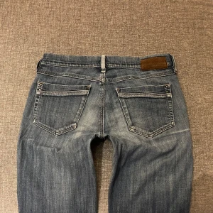 Low/Mid Rise Bootcut Jeans - Säljer ett par snygga blå bootcut jeans från Diesel med slitningar på framsidan. Jeansen är i normal passform och ser ut att vara i bra skick. Stretchigt material, midjemått ca 38 Innerbenslängd ca 86 💕 Jag är 165