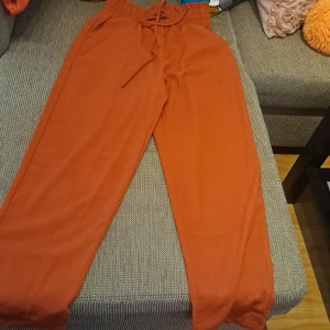 Orange mjukisbyxor med snörning - Säljer ett par superbekväma orange mjukisbyxor. De har en hög midja med snörning för bästa passform. Perfekta för en avslappnad dag hemma eller en chill dag ute. Byxorna är i bra skick och gjorda av mjukt material som känns skönt mot huden. Oanvänd. 