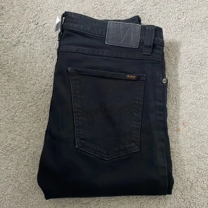Nudie jeans  - Säljer dessa helt svarta nudie jeans i storleken W32/L34. Skicket är 9,5/10. Modellen på byxorna är Thin Finn och personen på bilden är 184cm lång och väger 70kg. Nypris 1600kr, vårt pris 499kr. Tveka inte på att kontakta oss vid frågor🤝🔥👑🙌