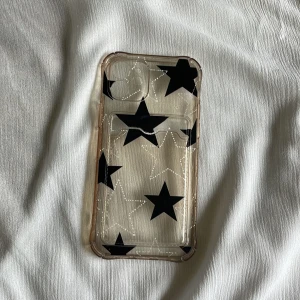 Genomskinligt mobilskal med svarta stjärnor - Säljer ett snyggt genomskinligt mobilskal med svarta stjärnor. Skalet är gjort av syntetmaterial och har en cool design med stjärnor som verkligen sticker ut. Perfekt för att skydda din mobil samtidigt som den ser stilren ut. Passar till iPhone.