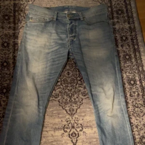 Diesel jeans - Säljer ett par snygga blå jeans från Diesel. De är i slim fit och har en cool, sliten look. Perfekta för både vardag och fest! De har en knappgylf och fem fickor. Märket Diesel syns tydligt på bakfickan och insidan av jeansen. Inga defekter eller något sådant Guzzmagnet självfallet. Dm vid frågor