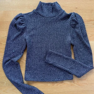 Glittrig polotröja från Divided - Säljer en superfin glittrig polotröja från hm i storlek XS. Tröjan är mörkgrå med glitter och har långa ärmar med puffiga axlar. Perfekt för festliga tillfällen eller när du vill glittra lite extra i vardagen! ✨