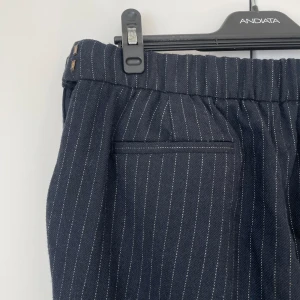 Kostymbyxor från Boomerang  - Kritstrecksrandiga kostymbyxor i blått och vitt. Storlek 38 (passar även 36) från Massimo Dutti. Fint skick. Materialet är ylleblandning. 
