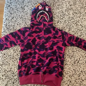 Bape color camo shark full zip up - Säljer då jag inte vill ha den längre, inga fläckar eller tecken på användning  , bra kvalite och skön size Medium fast skulle säga att den passar Small bra också. Tveka inte på att skicka ett meddelande om du har frågor/bud   OBS 1-till-1