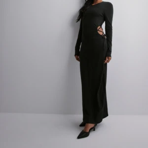 Långklänning med knytdetalj i sidan  - Jättesnygg svart långklänning med knytdetalj i sidan. Helt ny. Lappen kvar. Storlek m. 