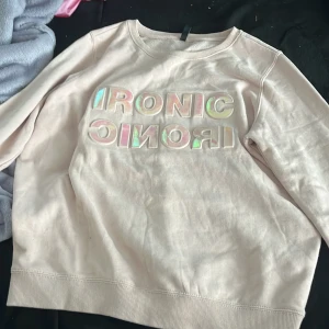 Rosa kofta med text - En rosa kofta med texten ”Ironic” i storlek M . Säljer eftersom den är stor på mig