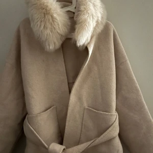 Vit pälskappa  - Vit/ beige kappa med päls. Använd i ett år! Säljer då den inte kommer till användning längre.  One size så passar alla 