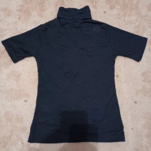 Mörkblå marinblå tajt t-shirt med krage - Säljer denna marinblåa ganska tajta t-shirten då den inte används. OBS har en lite ljusare fläck som syns på bild två, därav priset. Tror säkert den går att få bort men har inte provat. Köparen står för frakten och jag ansvarar ej för postens slarv. 