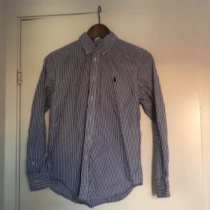 Blå Polo Ralph lauren skjorta  - Tjena säljer min randiga blåa Ralph lauren skjorta eftersom den har blivit för liten. Nypris är ca 1000 kr men säljer min för 349 .priset kan diskuteras, skicket är väldigt bra.