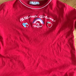 Röd croppad topp - Röd croppad top med tryck på ”ultimate girlwear” väldigt liten i moddellen. 