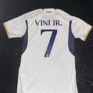 Vini Jr Real Madrid tröja - En mycket fin Vini Jr 2023/24 hemmatröja. Mycket bra skick, knappt använd. Tröjan är Player Version och har även Champions League patch på ärmen. Storlek S, hör av er vid frågor! :)