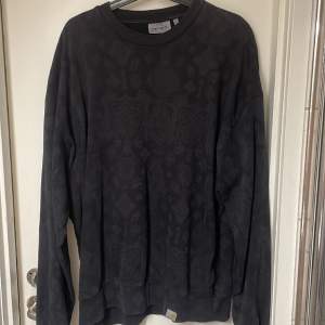 Snygg svart sweatshirt från carhartt med mönster på, mönstrerna syns inte så mycket. Använder aldirg längre, därför jag säljer.  Strl L, sitter lite baggy. Skick 9/10  Nypris runt 1000kr 