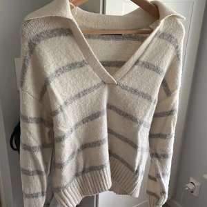 stickad tröja  - Sticka stödja med rönder från gina, har en v urringning med en liten krage där bak. Typ gul/beige med ljusgråa ränder💞xxs men sitter som en xs