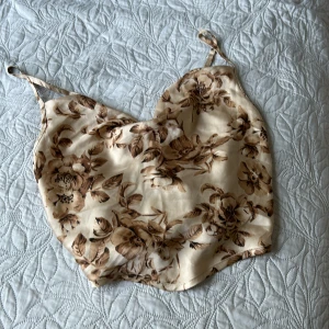 Blommig silkes topp! - En silkes topp med mönster på. Man knyter den där bak och banden går att justera. Har aldrig använt den! 