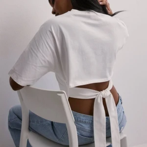 Open back tie tee nelly  - Säljer denna t-shirten som man knyter där bak från Nelly, knappt använd. (Däremot har den en jätte liten sminkfläck som knappt syns men man kan se på sista bilden) Strl M men passar även Xs/S