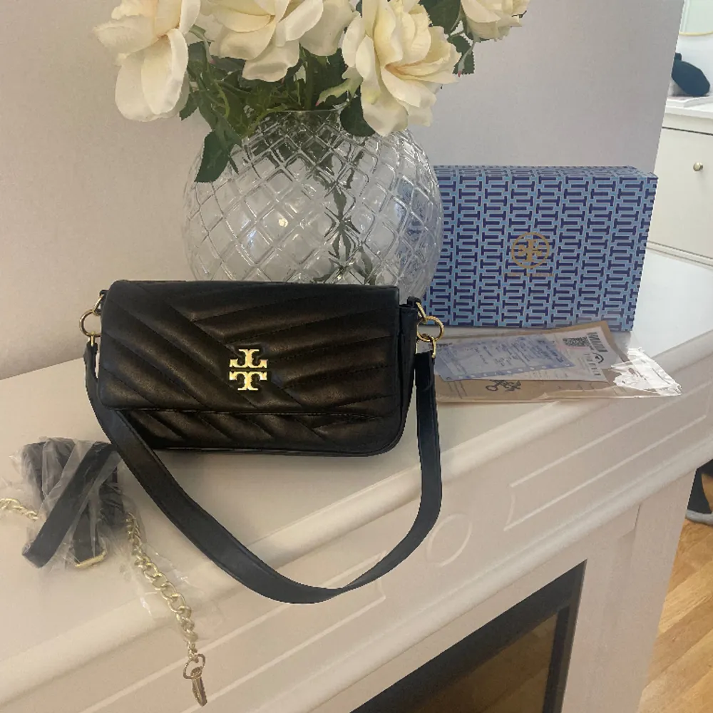 Säljer denna tory burch väskan (kopia). Det medföljer box, kvitto, papper mm. Finns ett kort band som sitter på väskan och ett längre som man kan se på bilden. Den är aldrig använd och jätte fin i skicket! . Väskor.