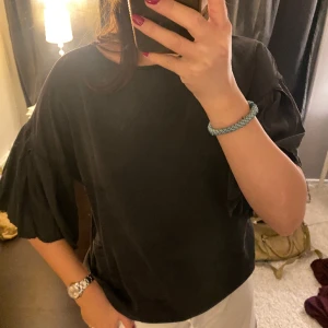 Blus - Så fin blus/tshirt med ”volanger” som armar! Köpt på arkivet och är i mycket bra skick💞svart/grå