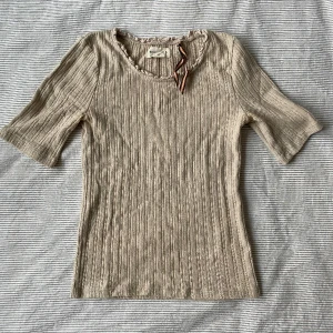 Beige T-shirt  - En jättefin beige T-shirt i ett super fint material och skick! Den har blivit använd fåtal gånger men käns nästan som ny! Passar perfekt till allt och formar kroppen på ett jättefint sätt!