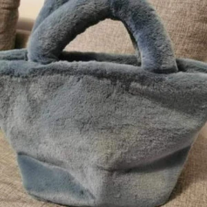 Mysig väska - Blå mysig väska från NA-KD. Aldrig använd. Ny utan prislapp. Jätte fin mild blå färg, som är passar perfekt för höst och vinter säsongen. Nypris 299kr 