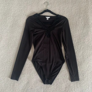 H&M svart body med spetskant  - Body från H&M med spetskant. Använd enstaka gång. Utan anmärkningar. Storlek XS men passar även S då den är stretchig.
