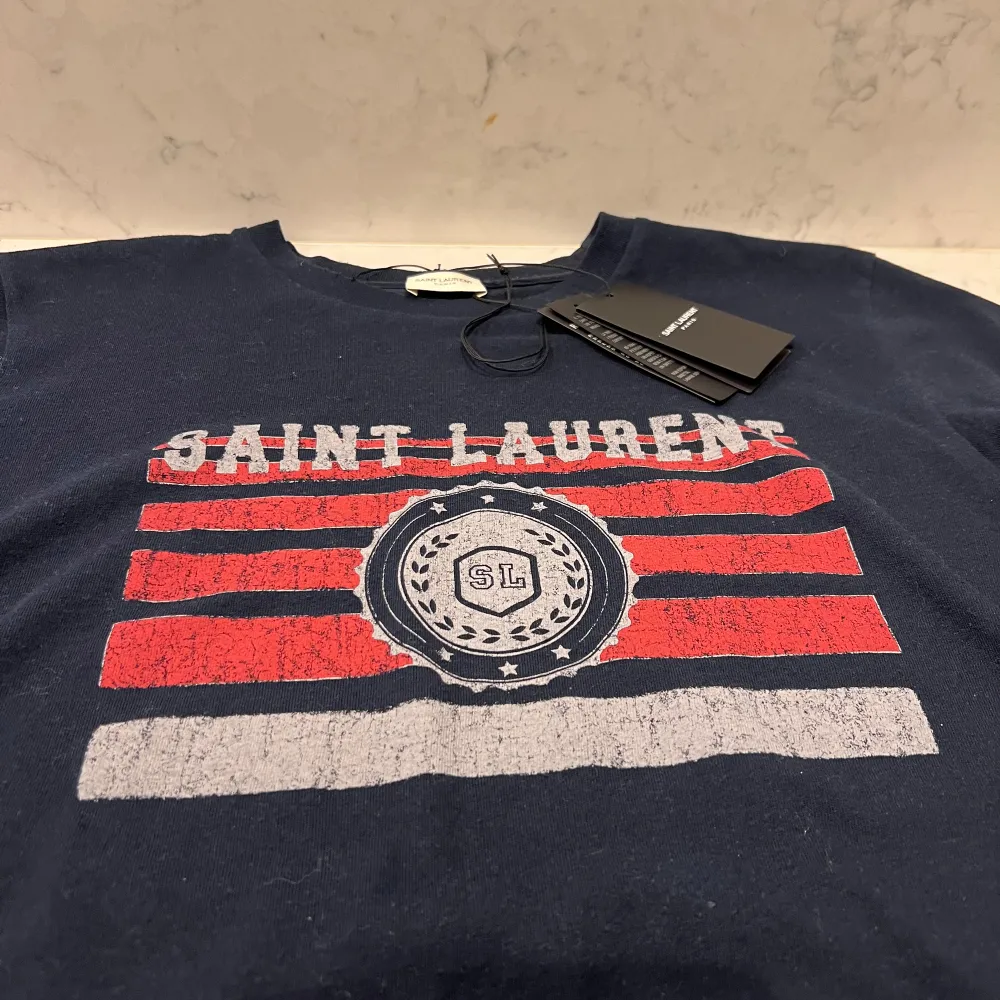 Säljer denna eftertraktade tshirten från saint Laurent. Som ny, använd 2 ggr. Storlek L passar lite mindre. Tags medföljer vid köp.. T-shirts.
