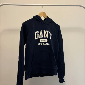 Navy Gant hoodie - Navy luvtröja från Gant. Strlk 158-164 Fin hoodie som sitter som den ska och har en liten vintage touch till sig. Bra passtil till stroleksmotten. Passar väldigt till vilka byxor som helst. 