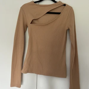 Topp med skurning  - Beige topp med skurning vid brösten 