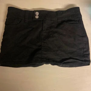 svart mini jeanskjol - Som ny, knappt användt. Den är sjukt snygg och ganska kort. Har två knappar som sitter snett och en knapp på insidan så den sitter bättre🔥