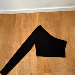 Topp med en arm  - Svart ribbad topp. Kommer aldrig till användning och bara använd 1 gång.  Storlek 32/34
