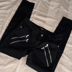 Stretchiga svarta coola jeans med dragkedjor - Svarta coola stretchiga byxor från bikbok med dragkedjor på framsidan och fickor på baksidan. Aldrig använda. Storlek M, kan passa S beror på kroppsform 🖤✨