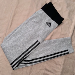 Grå Adidas leggings med svarta streck nya - Gråa adidas leggings / tights med svarta streck. Storlek S men passar XS och lite mindre. De är aldrig använda, nyskick. 