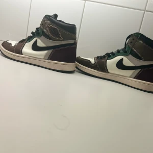 Nike Air Jordan 1 Retro High OG “Handcrafted” - bra skick: Säljer ett par Nike Air Jordan 1 Retro High OG “Handcrafted”. Dessa sneakers är en del av den populära Air Jordan-serien och har en unik färgkombinat.De är utrustade med en vadderad krage för extra komfort och har den klassiska Nike Air-lo