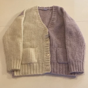 Stickad kofta storlek 134:140 - En stickad kofta i färg vitt och ljus lila. Den har aldrig kommit till användning. Storlek 134/140. 