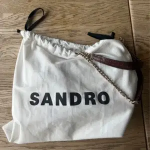 Vinröd/brun väska från Sandro. Använd en del men i bra skick! Har flera bilder om det önskas!