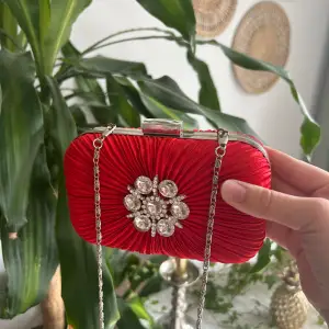 Denna charmiga röda väskan har aldrig använts, den är tålig och gjord av metall med jätte fint tyg runt om. Är osäker på vart den är köpt då det inte står något på den.
