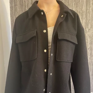 Svart kappa från Gina Tricot - En svart kappa med silvriga knappar som är köpt på Gina Tricot. Storlek M men passar mig som vanligtvis har storlek XS-S. Inga defekter eller hål, något nopprig men ingenting man tänker på! Hör av er för frågor/ fler bilder!💕