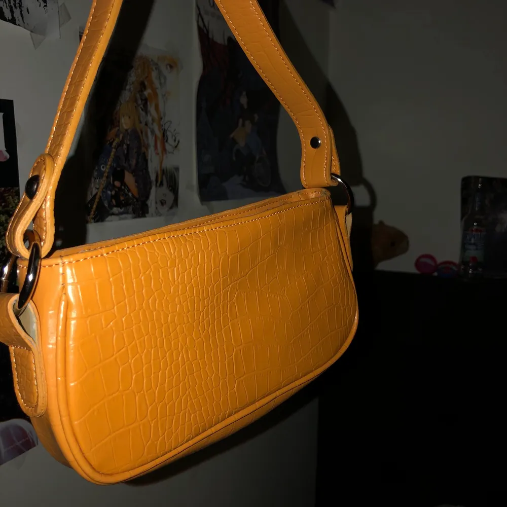 En orange axelväska från asos. Så gott som ny, aldrig använd. Den är perfekt för att kunna ha med sig mobilen och viktiga kort:). Väskor.
