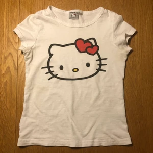 Hello kitty babytee - Supersöt t-shirt med hello kitty på, köpt här på Plick! Tröjan är barnstorlek 122/128, men passar som croppad xxs-xs. Älskar verkligen den här tröjan men den är för liten för mig💓💓