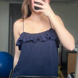 Topp med volang - Söt marinblå topp med volang och tunna band, från Mango! Inte använd på ett bra tag och finns inga tecken på slitage. Köparen står för frakten❤️