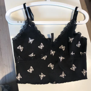 Svart linne med spets - Det är ett väldigt fint linne i storlek M med vacker spets och vita fjärilar som detaljer. Plagget är ifrån h&m. Man kan sjustera banden så att passformen blir mer anpassad för den som bär den. Jag har haft linnet i ungefär ett år men använder det inte lika mycket längre. Passar perfekt för varma sommardagar!☀️           