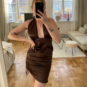 Brun klänning i silke - Säljes tyvärr pga för liten, aldrig använd och prislapp sitter kvar. Köpt från BikBok nypris 399kr. Har drapering vid sidan som man kan justera lite som man vill.