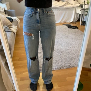 Gina 90s jeans - Ljusblåa högmidjade jeans från Gina tricot! Hål i knäna och låret, storlek 32. Säljer på grund av att de är för långa på mig ☺️använda ungefär 5 gånger så de är så gott som nya!