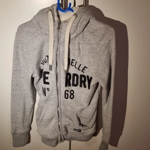 Superdry kofta str: M - En grå ish fluffig vinterkofta, storlek M med luva.