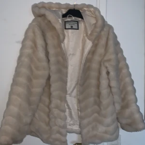 Sockervit pälsjacka  - Denna jacka är riktigt snygg på. Den är använt ett fåtal gånger men kommer inte längre till använding. Den är lite sliten på insidan men det är inget som syns när man har på den, eller utifrån. Stilren jacka med fin huva och två djupa fickor.