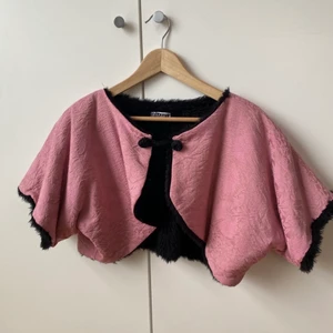 Remake bolero - Världens härligaste Remake bolero från Stadsmissionen! Snyggt rosa tyg med svart fuskpäls på insidan. Storlek saknas men uppskattas till en M, fungerar som over size på en S. Materiallapp saknas. Tjockt tyg. Gamla tyger men den har bara hängt i garderoben hos mig. Jag hittar ingenting att anmärka på.