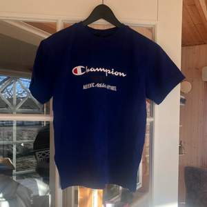 Electric blue champion-tshirt. Fint skick förutom att lappen är trasig, därför uppskattad storlek. Passar bra på mig som är en M, men passar även mindre storlekar om man vill ha den lite mer oversize!