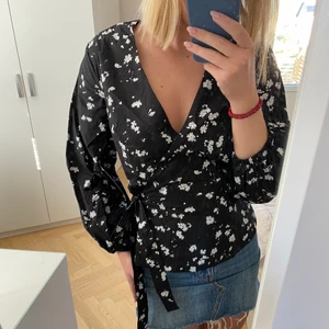 Blommig blus från Carin Wester - Säljer denna svarta knytblus med vita blommor i storlek 36. Den har prislapp kvar och är aldrig använd.  En fraktkostnad tillkommer om inte annat är överenskommet