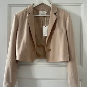 Cropped blazer beige - En helt fantastisk croppad blazer från Nelly. Aldrig använd. Strl 40. Ord. Pris 499kr
